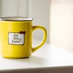 An image of a bright yellow ceramic coffee mug, sitting on a wooden surface, with the words 'Did You Know?' written on it."