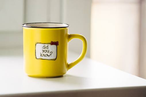 An image of a bright yellow ceramic coffee mug, sitting on a wooden surface, with the words 'Did You Know?' written on it."